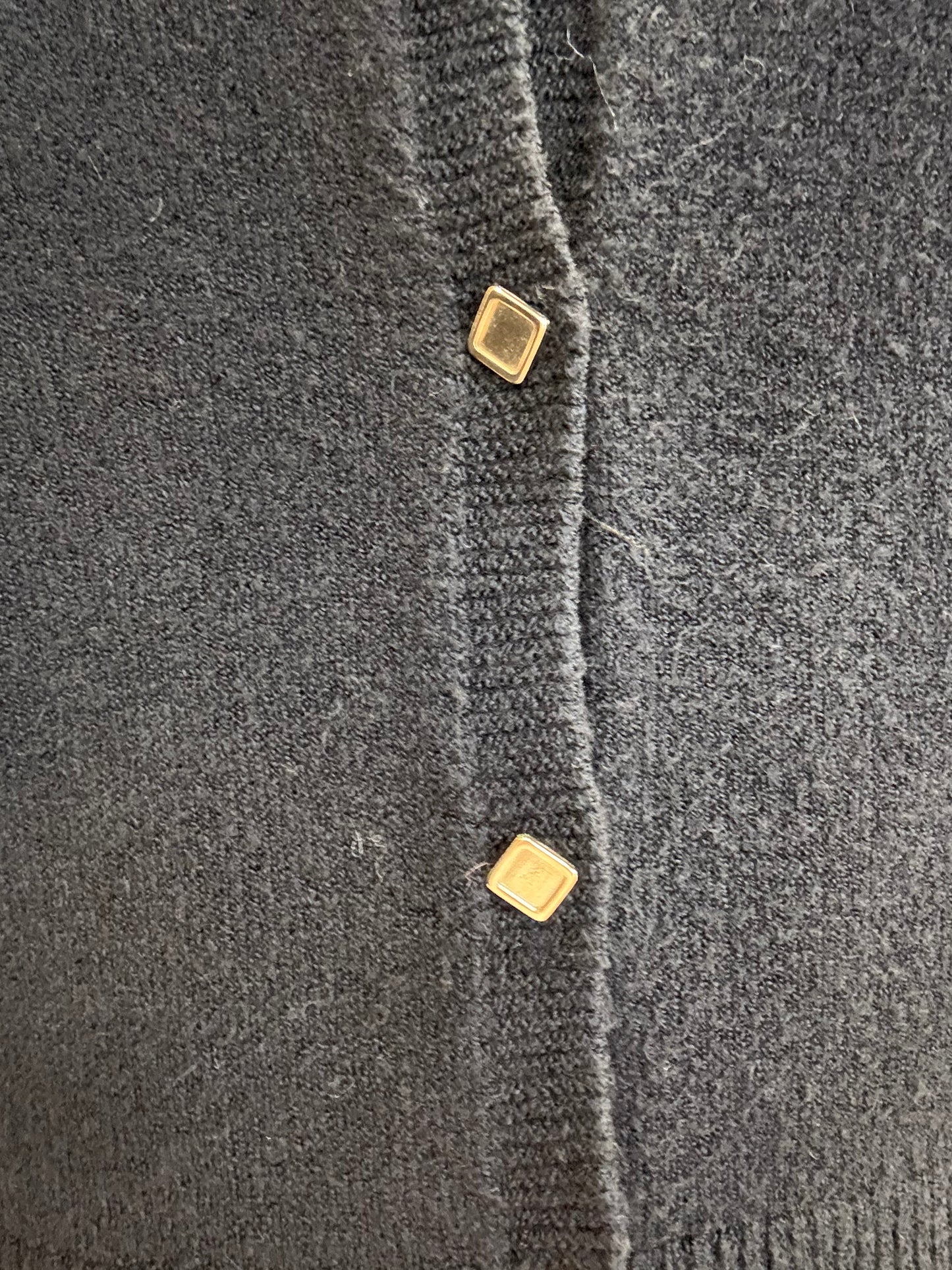 Dettaglio di cardigan corto nero con bottoncini dorati di ECO, materiale morbido e accogliente.