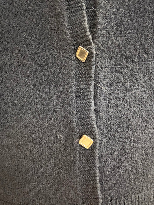 Dettaglio di cardigan corto nero con bottoncini dorati di ECO, materiale morbido e accogliente.