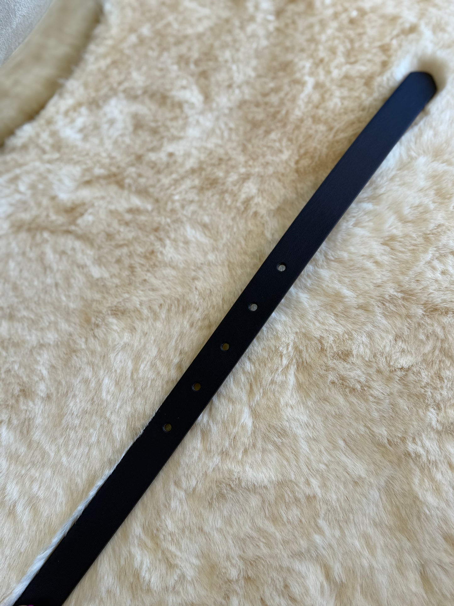 Cintura ecopelle nera hardware argento sottile su sfondo morbido