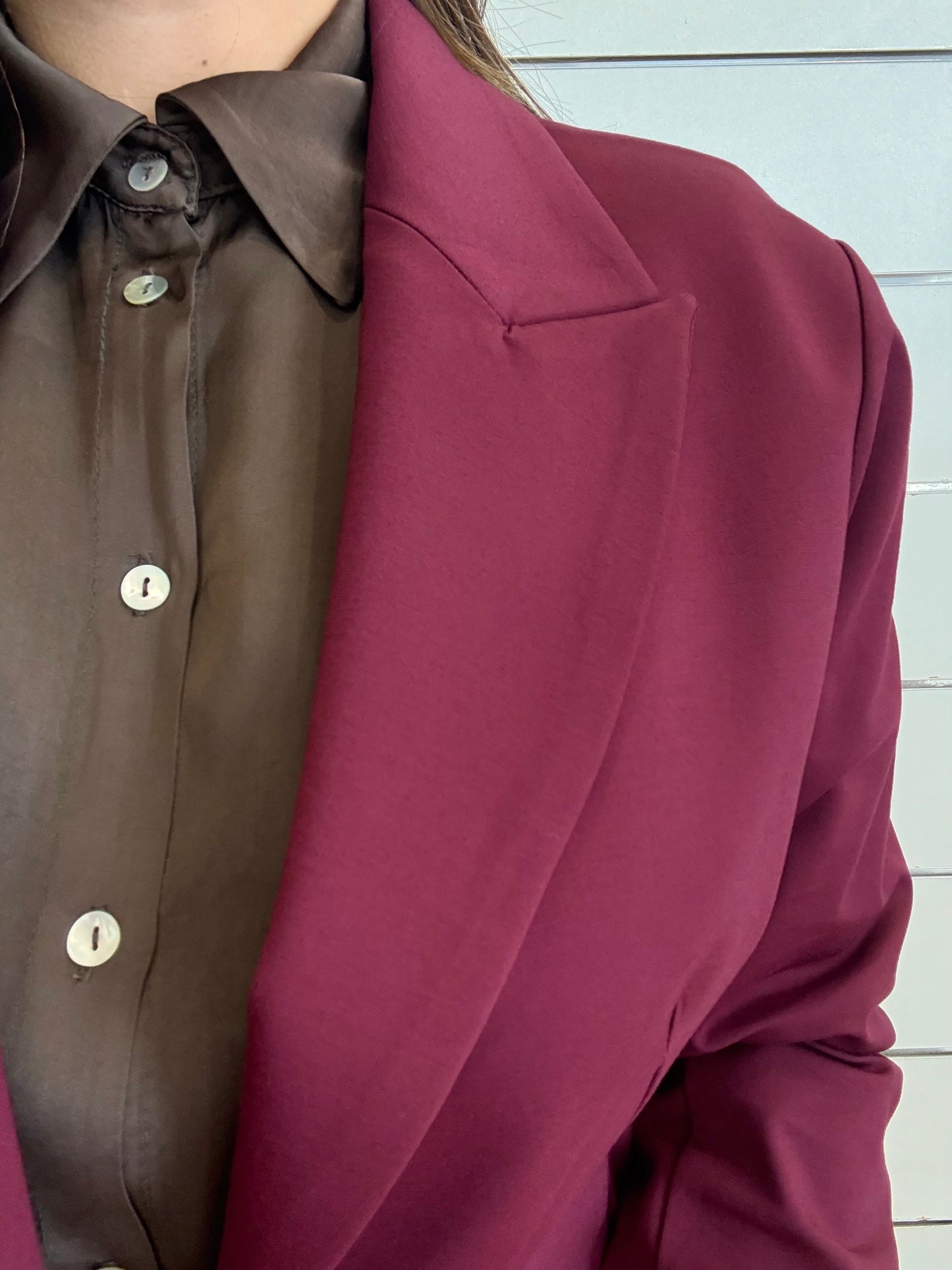 Giacca vinaccia con bottone ottonato indossata sopra una camicia marrone, elegante e alla moda