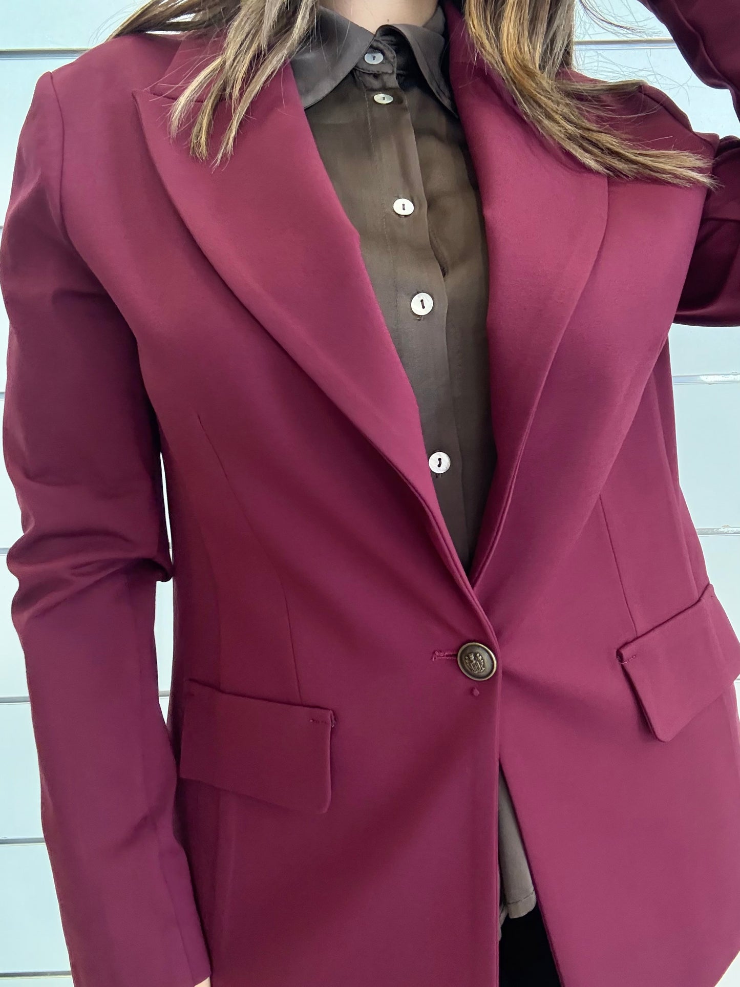 Giacca vinaccia con bottone ottonato indossata su camicia marrone elegante