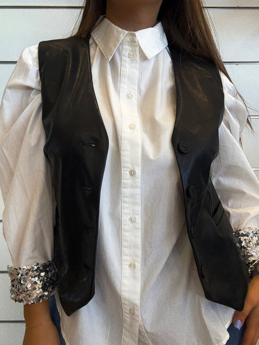Gilet corto in ecopelle nera con bottoni indossato sopra una camicia bianca elegante