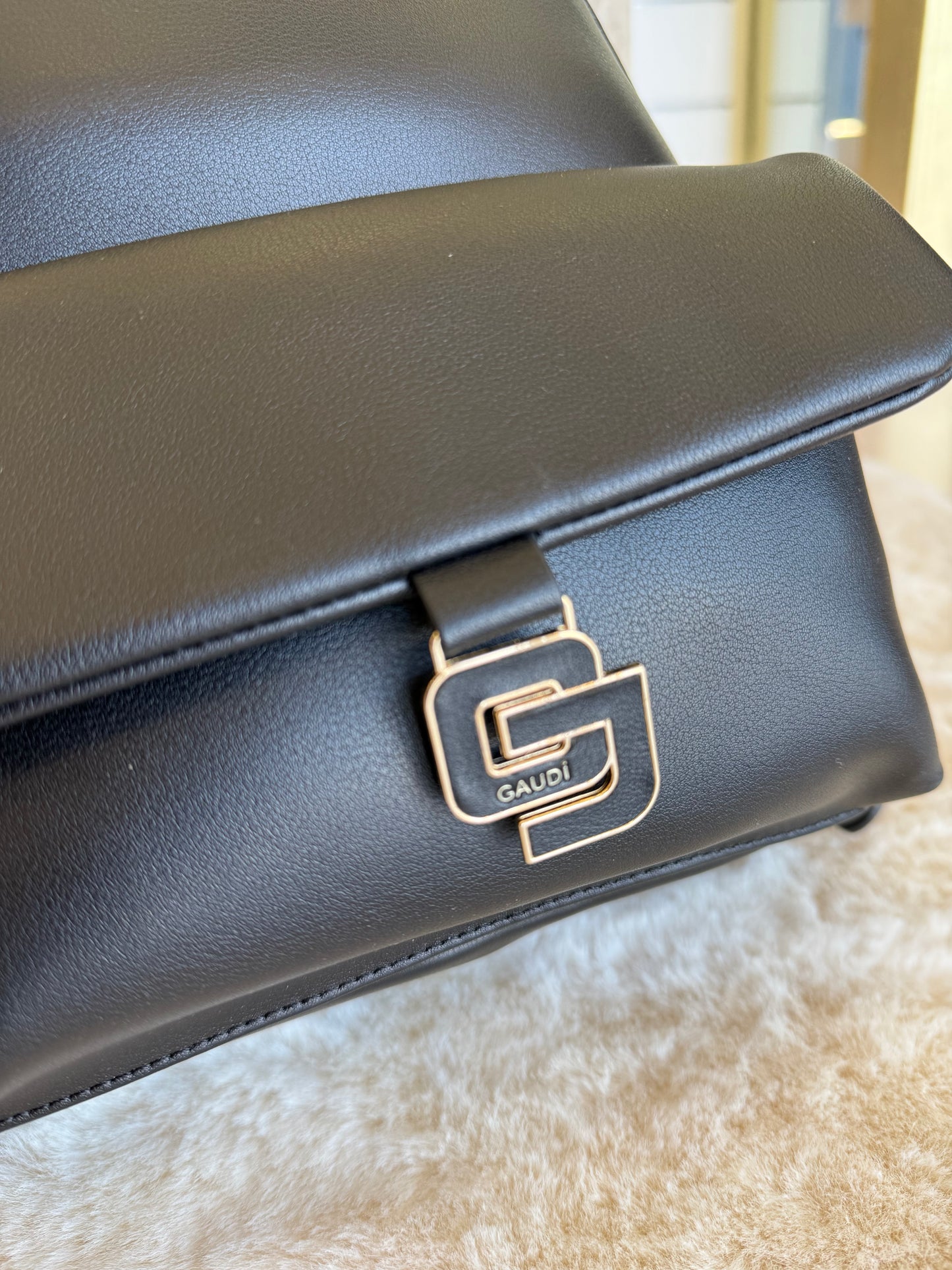 Dettaglio dello zaino nero in similpelle di Gaudì con logo elegante in metallo