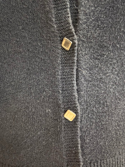 Dettaglio di cardigan corto nero con bottoncini dorati di ECO, materiale morbido e accogliente.