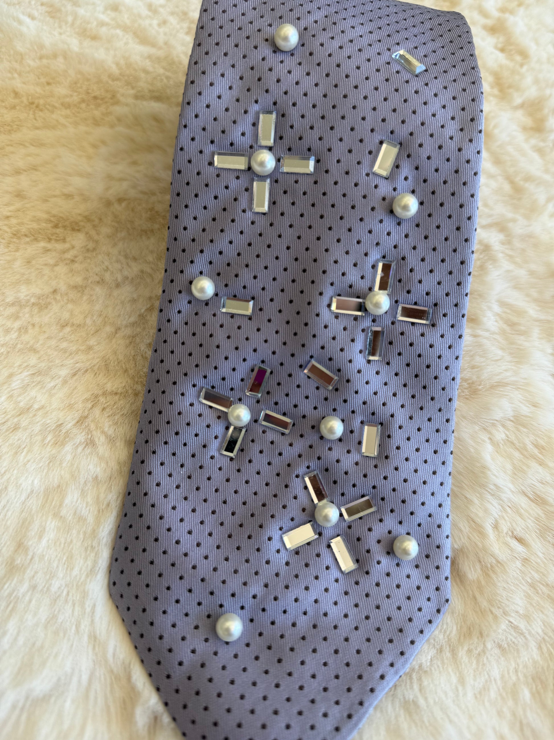Cravatta elegante da donna con decorazioni in perle e inserti metallici su sfondo grigio