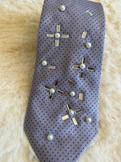 Cravatta elegante da donna con decorazioni in perle e inserti metallici su sfondo grigio