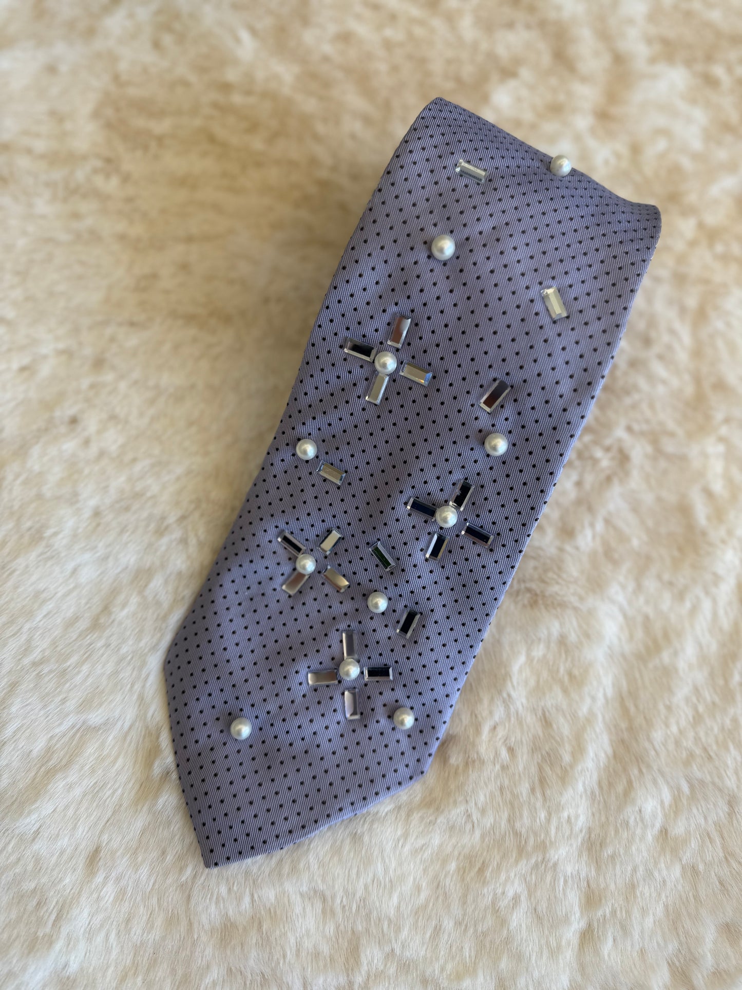 Cravatta elegante da donna con perle e dettagli brillanti su fondo grigio chiaro