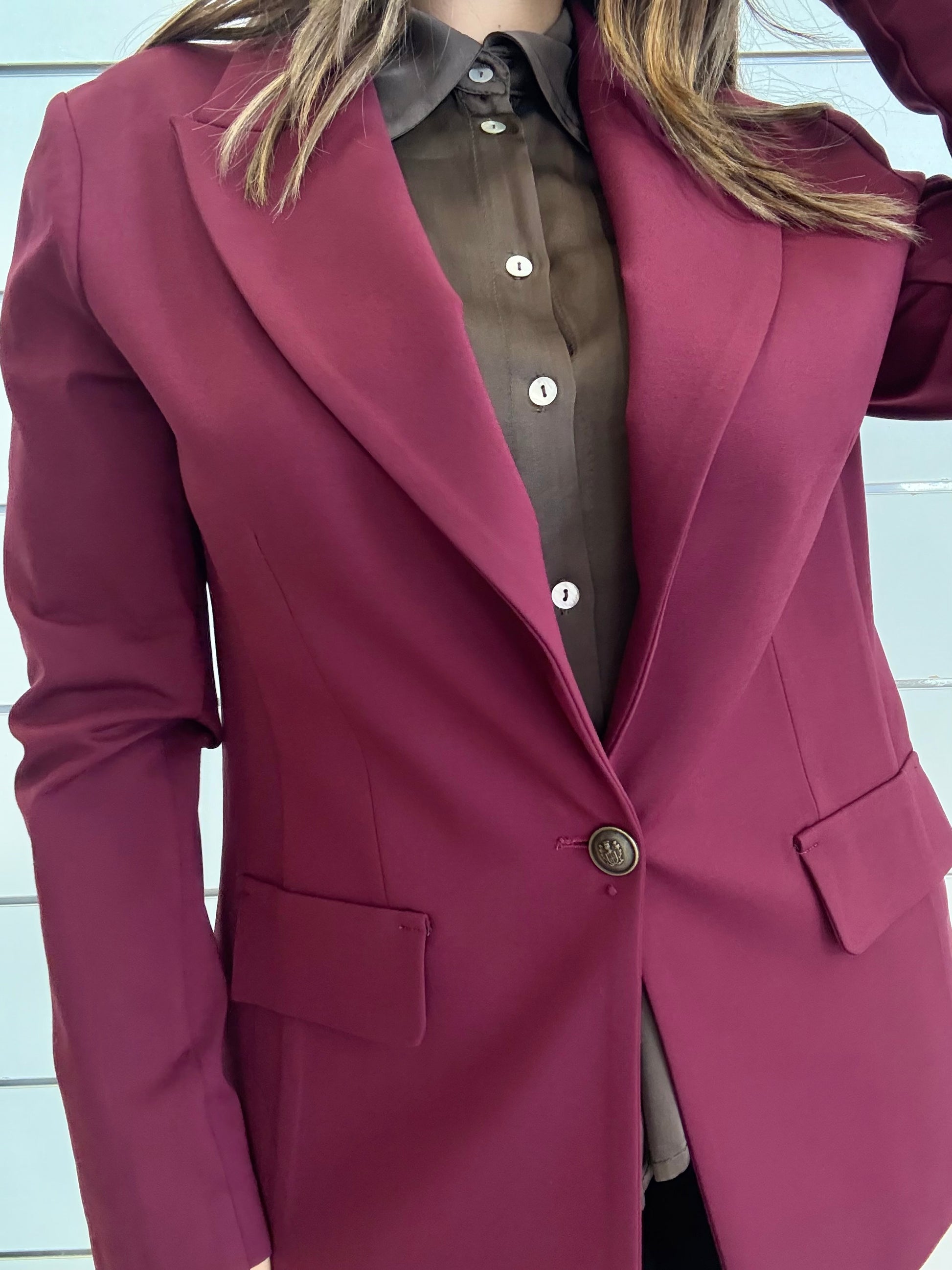 Giacca vinaccia con bottone ottonato indossata su camicia marrone elegante