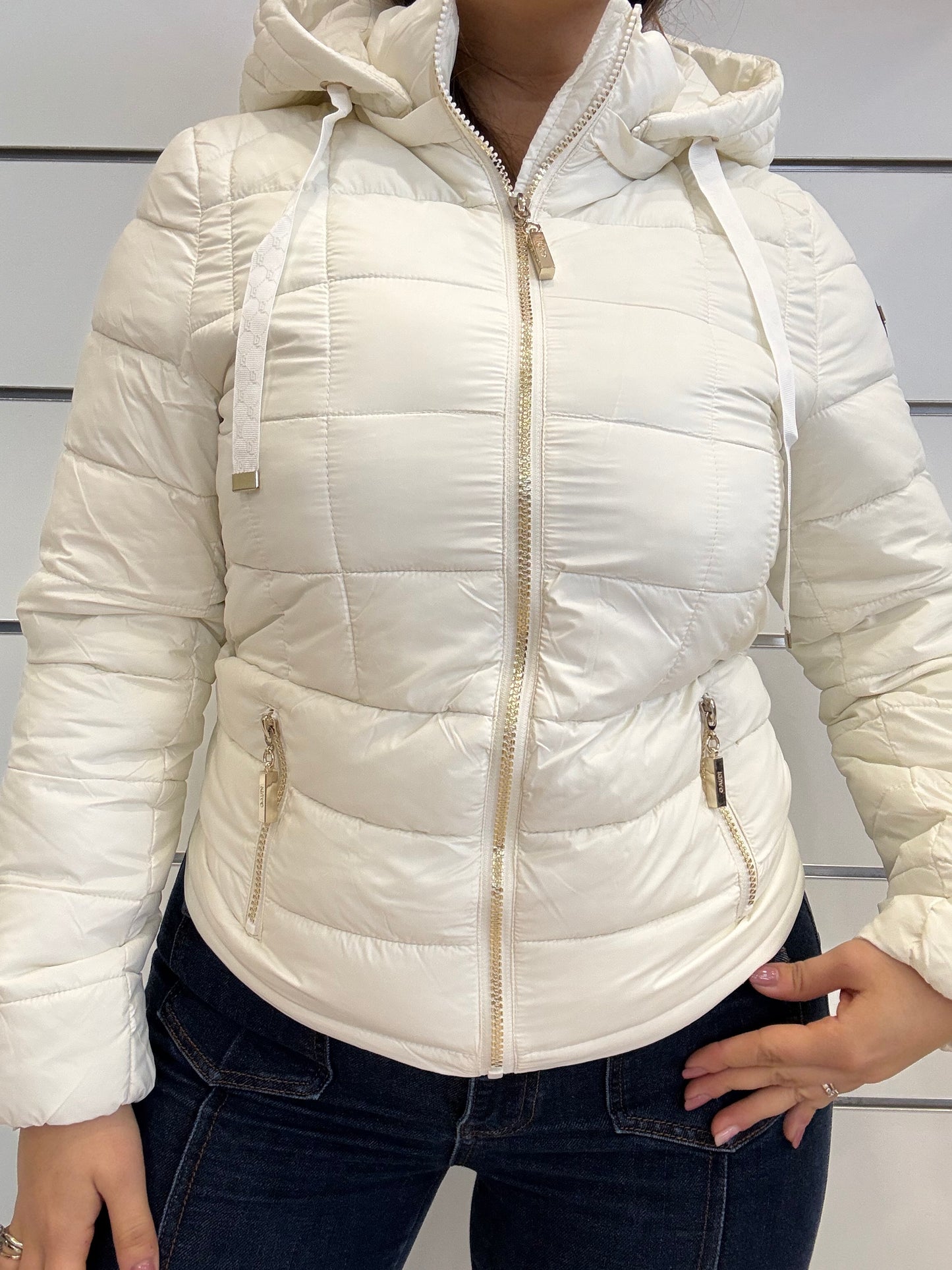 Piumino bianco da donna con cappuccio e zip, dal taglio corto e con dettagli eleganti.