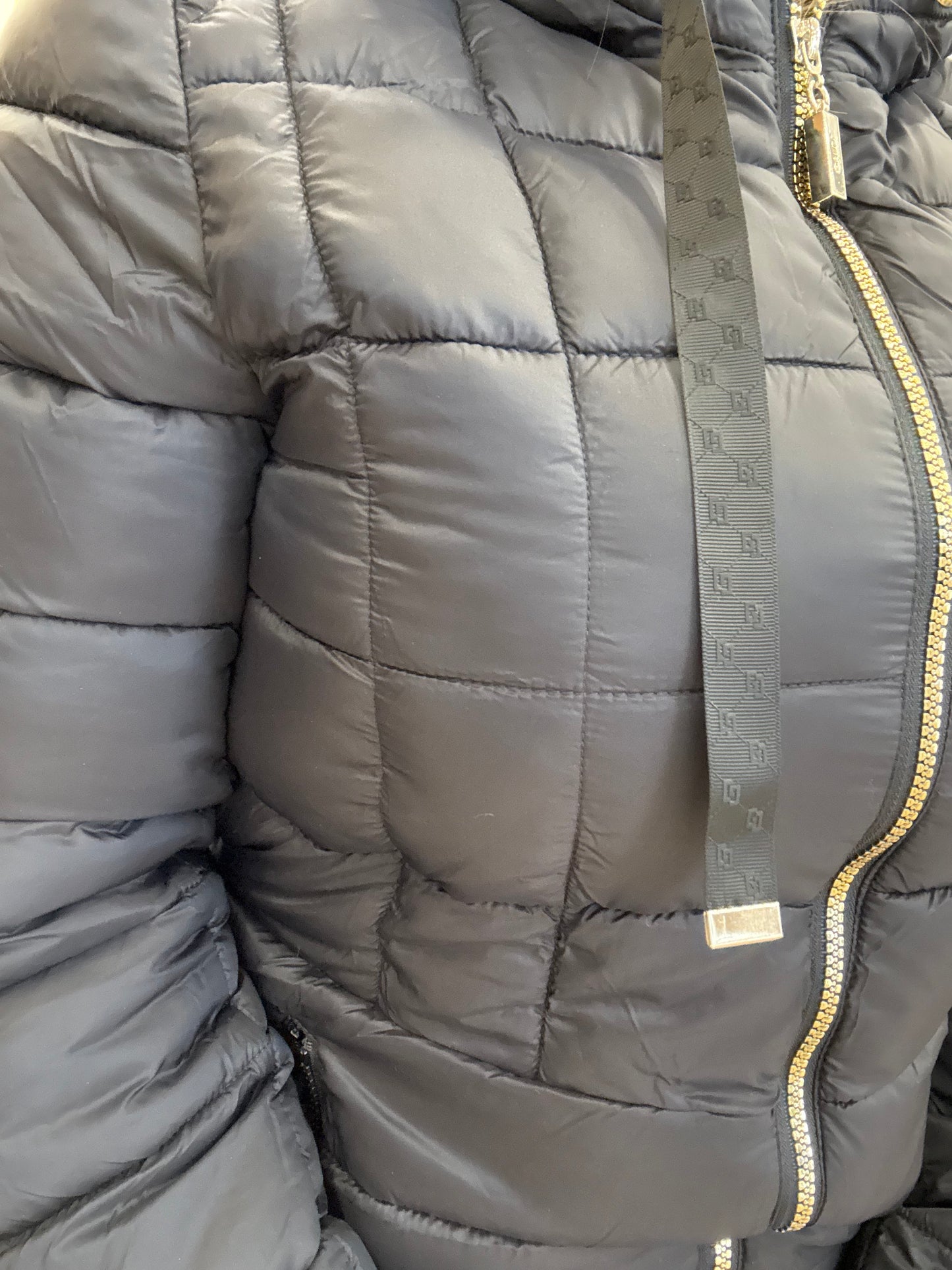 Piumino da donna trapuntato con cappuccio in tessuto grigio scuro, con zip e dettagli eleganti.