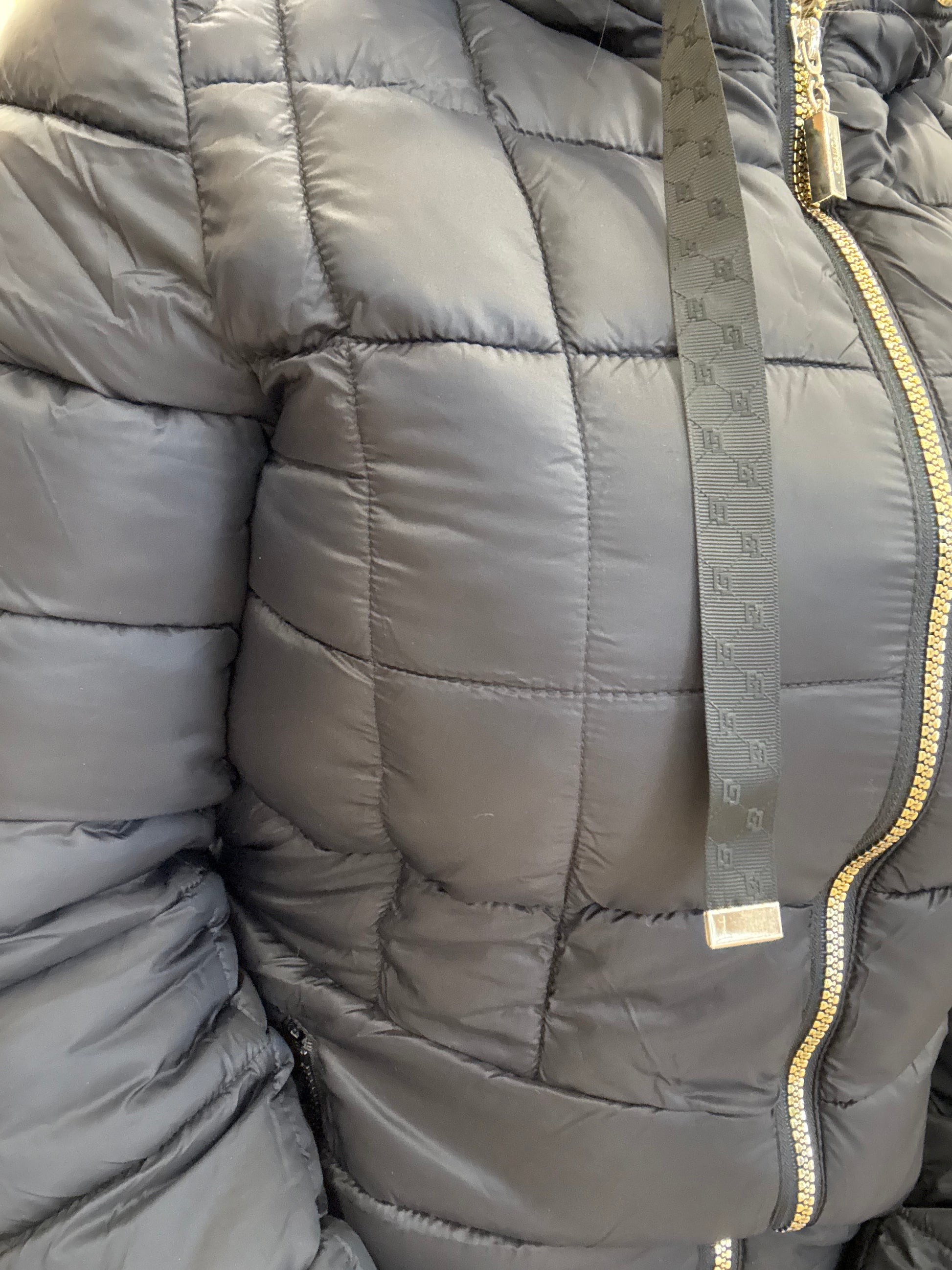 Piumino da donna trapuntato con cappuccio in tessuto grigio scuro, con zip e dettagli eleganti.